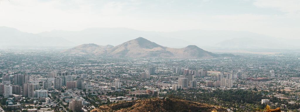 Vista amplia de Santiago desde un cerro, con los cerros del valle al fondo