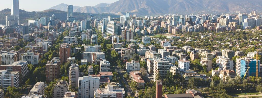 Vista aérea de barrios arbolados de Santiago con la cordillera al fondo